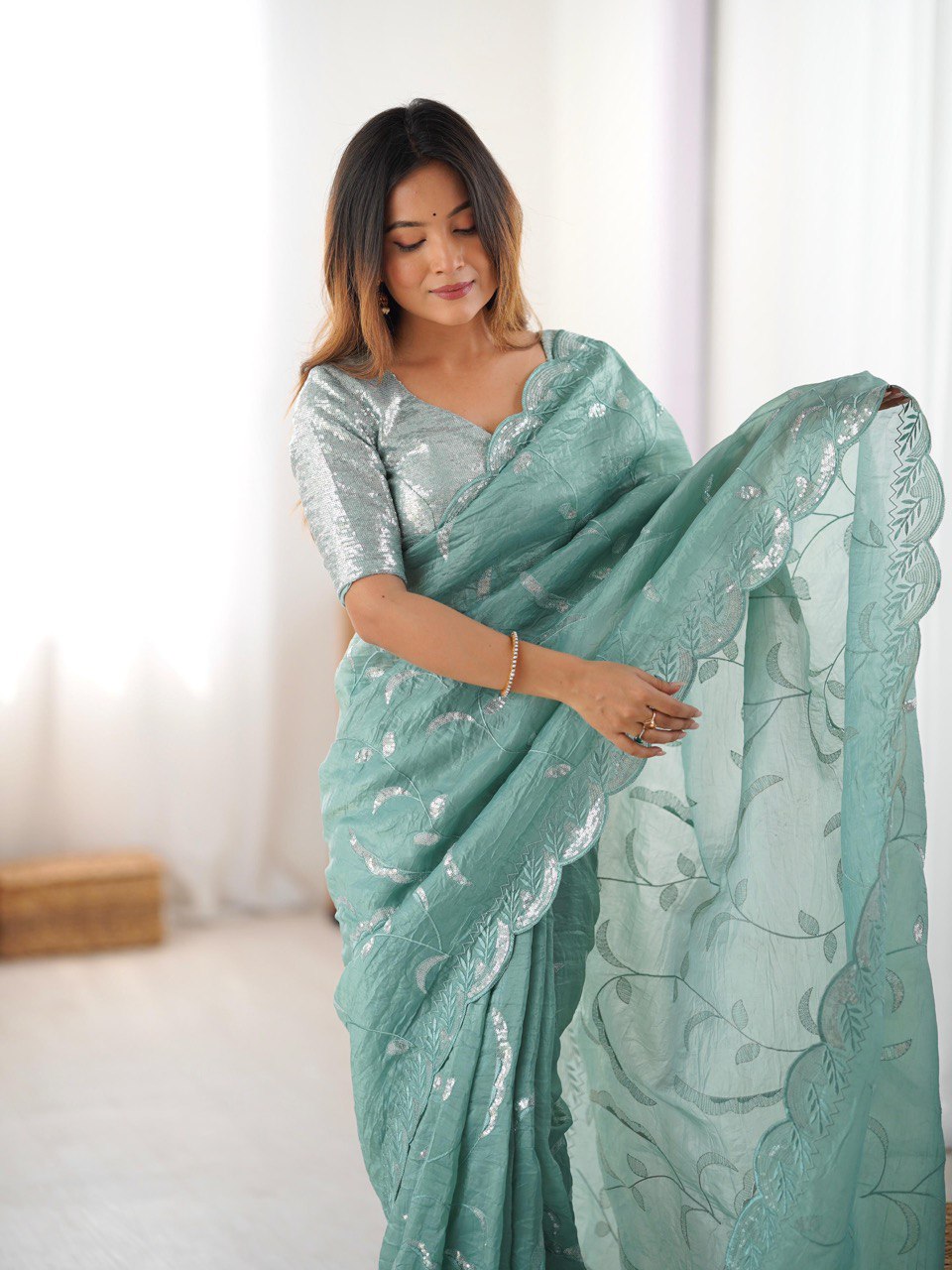 Woman wearing a light blue saree with a white border indoors