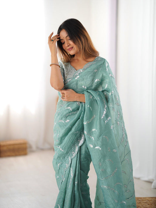 Woman wearing a light green saree with a subtle pattern