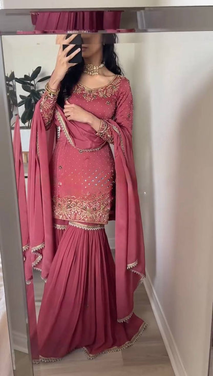 Person wearing a pink traditional outfit with gold embroidery i